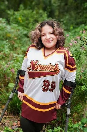 Woman in Norwich hockey jersey smiling outdoors.