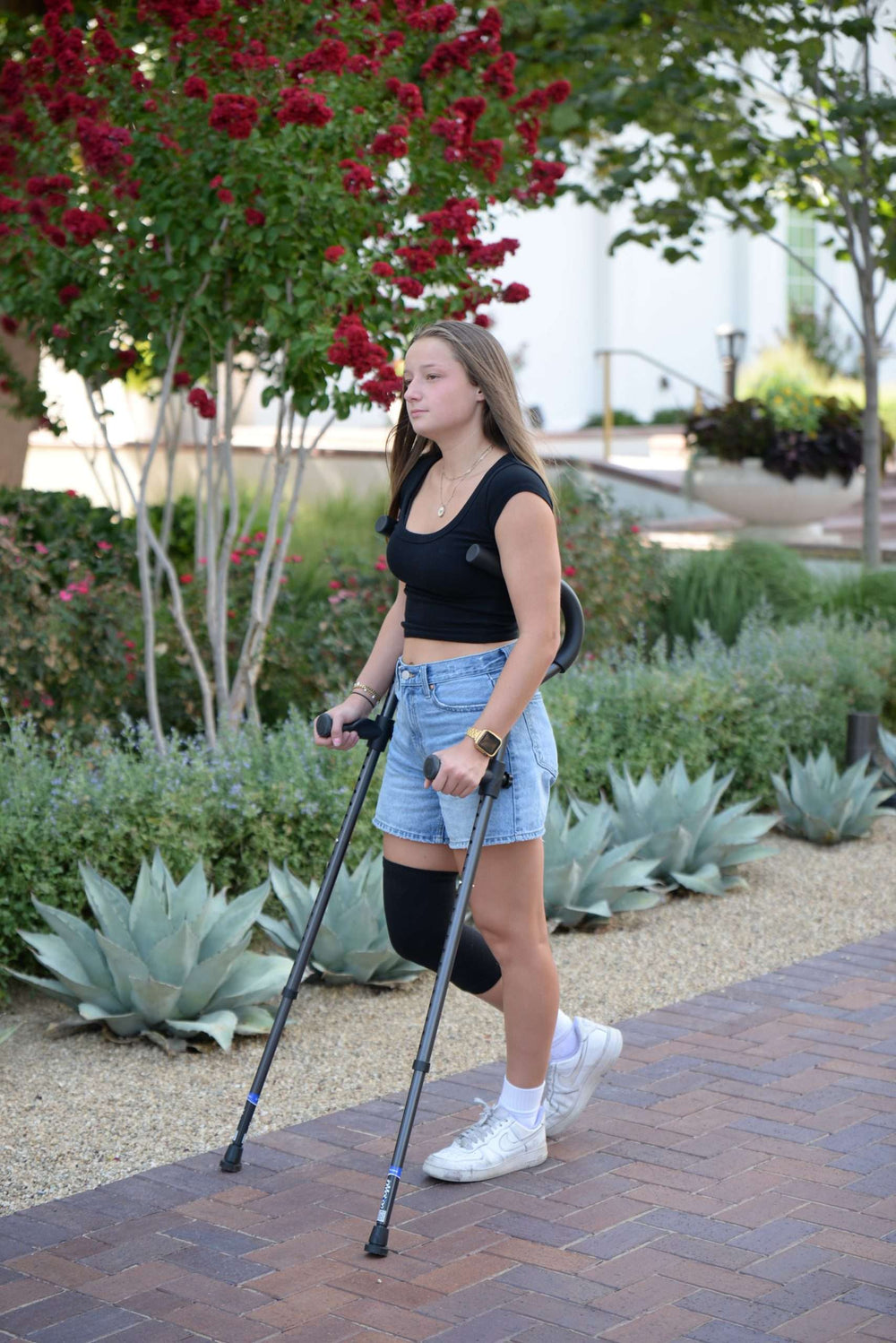 Young woman using crutches walking in garden