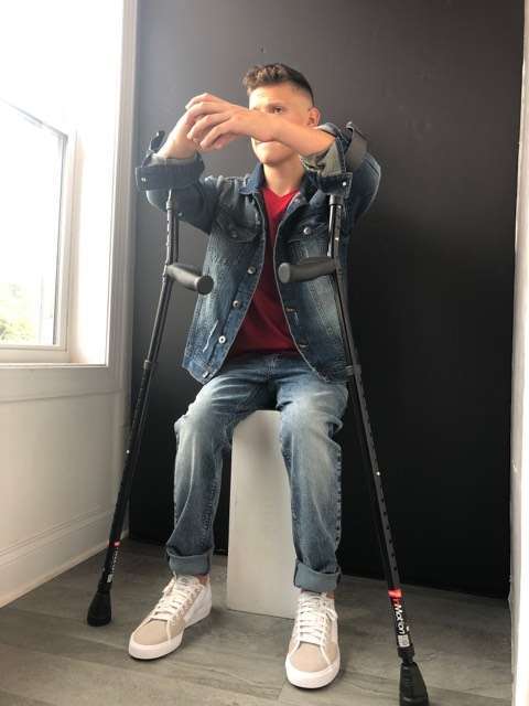 A young man posing with his in-motion forearm crutches.