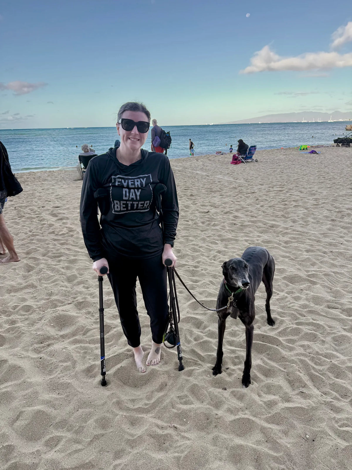 Woman with crutches and dog on beach.