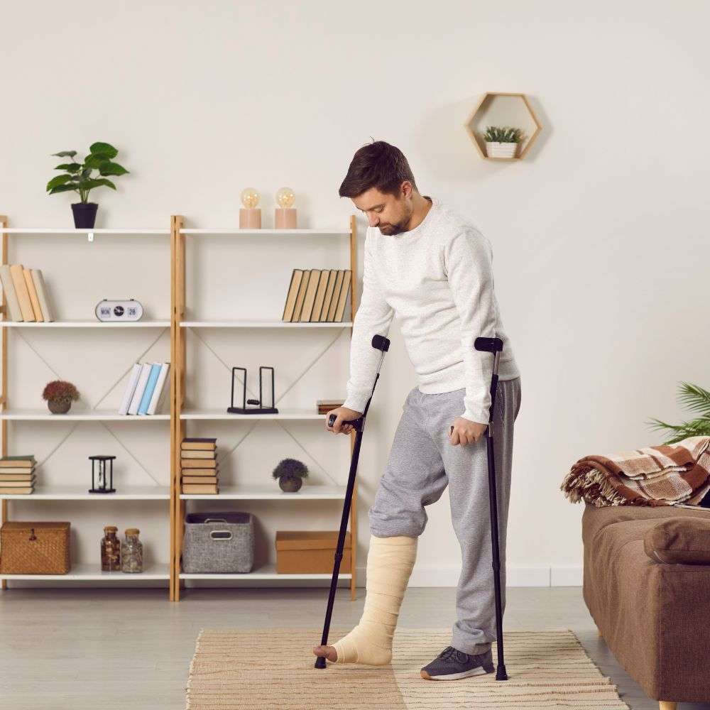 Man with crutches and leg cast in living room.