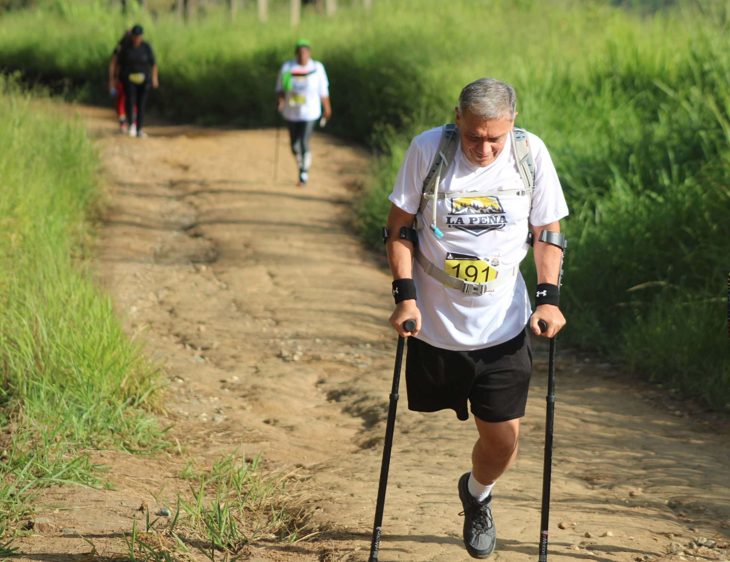 Man using crutches on dirt path during race.