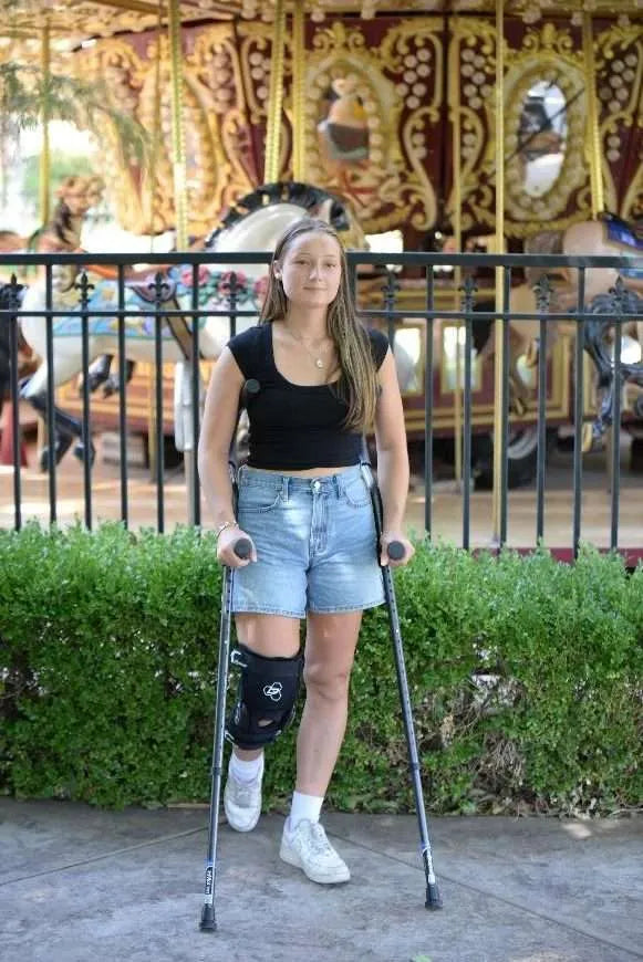 Woman on crutches by carousel