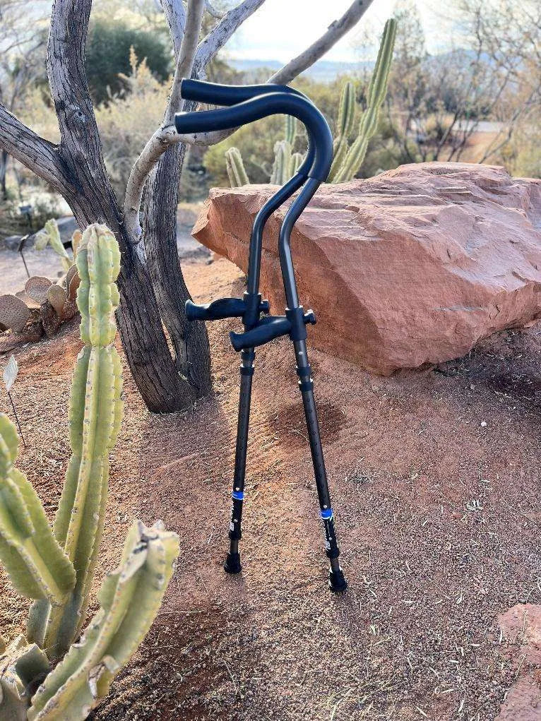 Black crutches leaning against rock, desert landscape background.