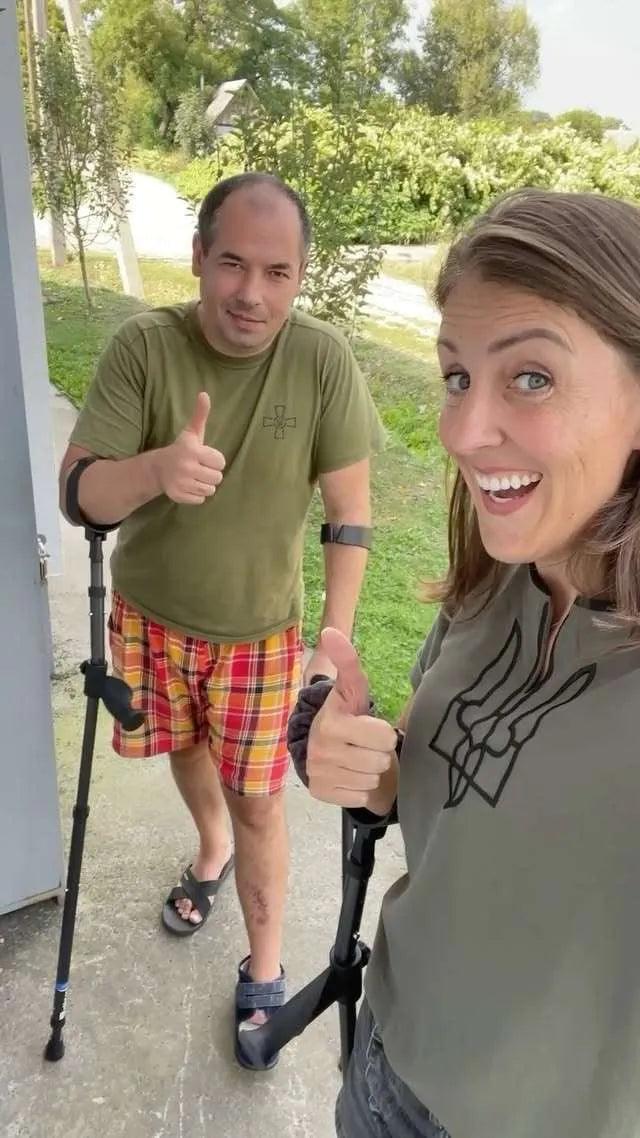 Two people smiling with thumbs up, using crutches.