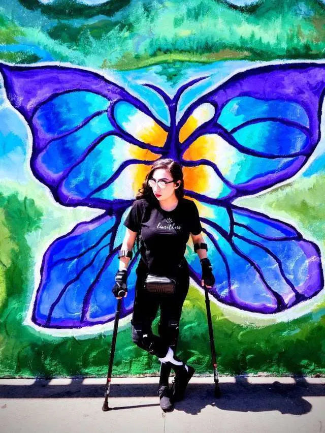 Person with crutches in front of colorful butterfly mural.