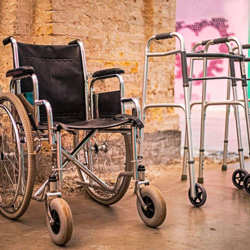 Wheelchair and walkers against rustic wall.