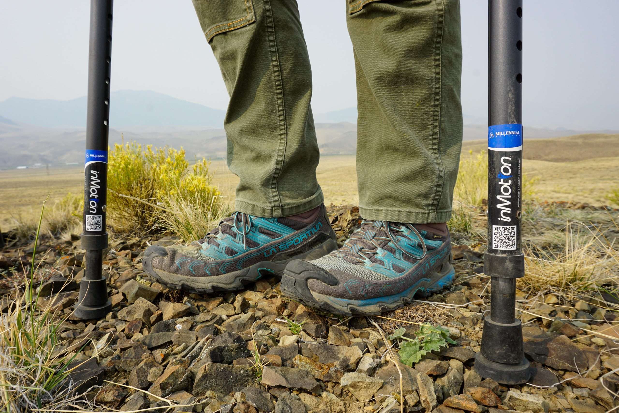 Close-up of hiking boots and in-Motion Pro forearm crutches on rocky terrain