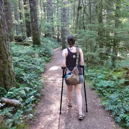 Person hiking a forest trail with in-Motion Pro forearm crutches