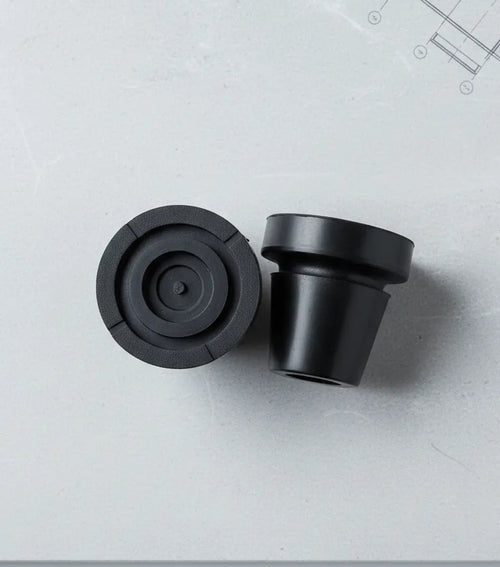 Pair of in-Motion articulating rubber crutch tips on a gray surface